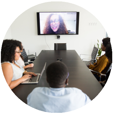 three people in  a meeting room, on screen is another person joining virtually